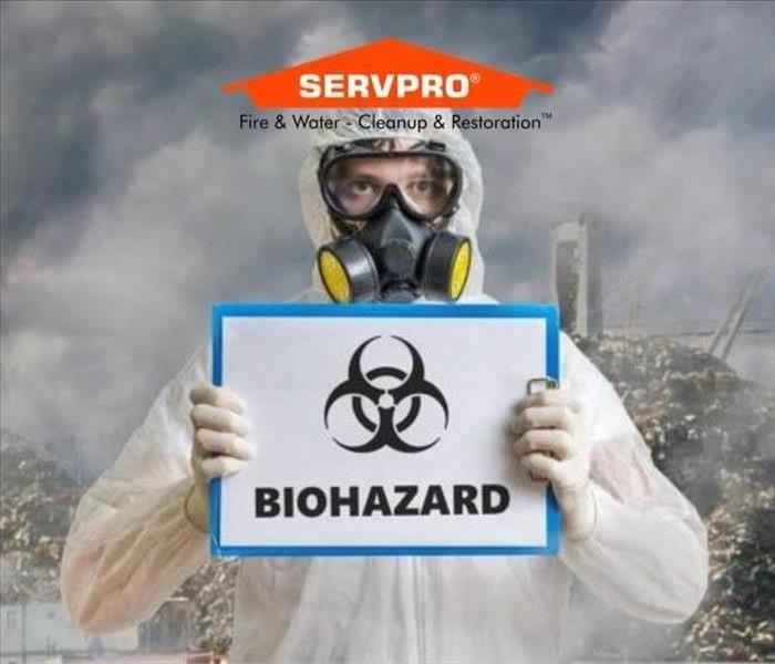 A man in a tyvek suit holding a biohazard sign